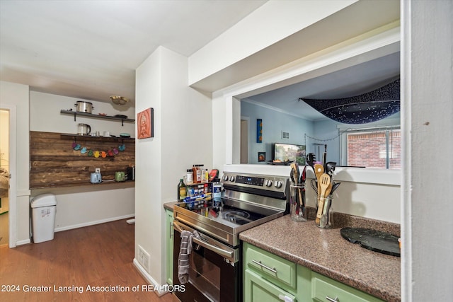 kitchen featuring green cabinetry, stainless steel electric range, dark wood-type flooring, and crown molding