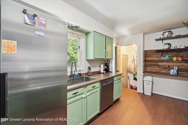 kitchen with appliances with stainless steel finishes, hardwood / wood-style floors, sink, and green cabinets