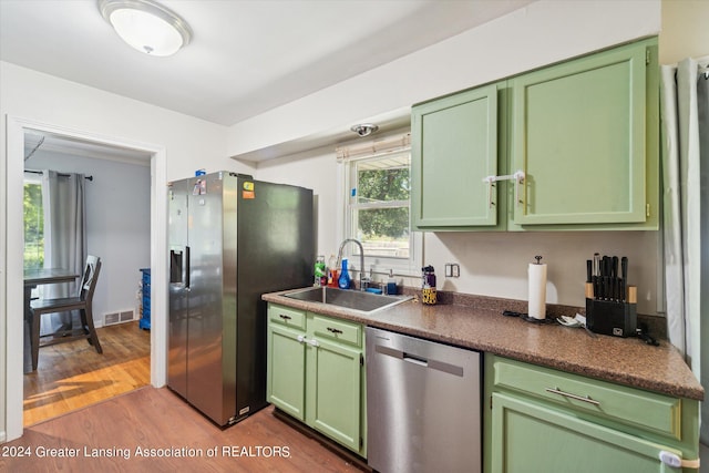 kitchen featuring green cabinetry, sink, appliances with stainless steel finishes, and hardwood / wood-style floors