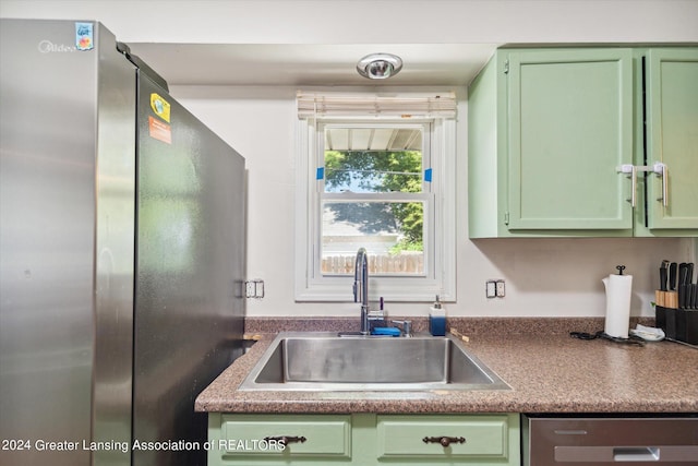 kitchen with green cabinetry, appliances with stainless steel finishes, and sink