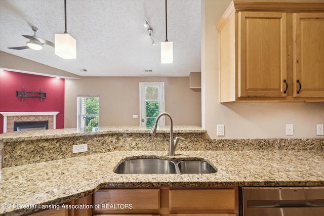 kitchen featuring sink, a fireplace, light stone countertops, track lighting, and a textured ceiling