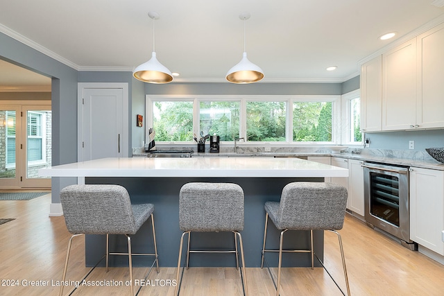 kitchen with a wealth of natural light, pendant lighting, wine cooler, and light hardwood / wood-style floors