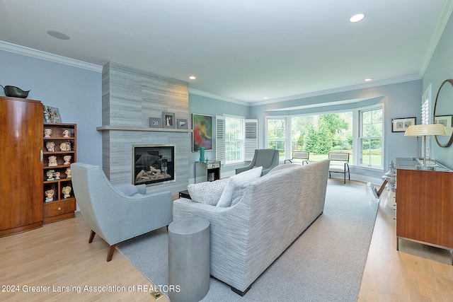 living room with a fireplace, ornamental molding, and light hardwood / wood-style flooring