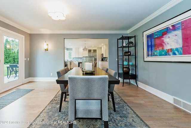 dining room with crown molding and light hardwood / wood-style floors