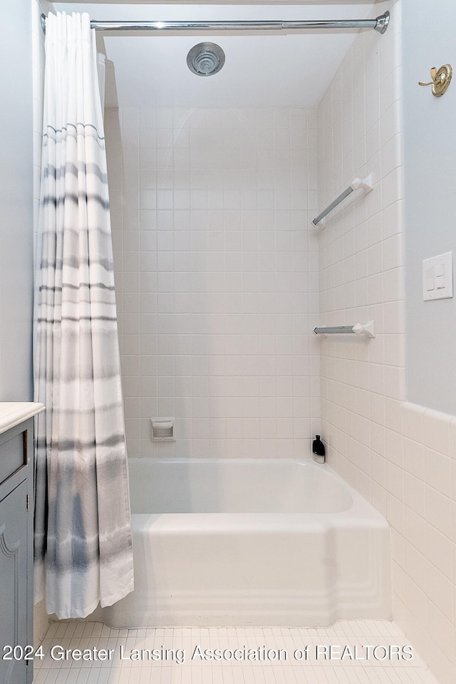 bathroom featuring tile patterned floors, shower / bath combo, tile walls, and vanity