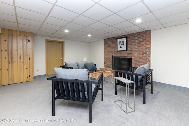 carpeted living room featuring a fireplace and a drop ceiling