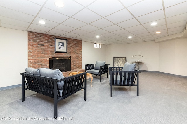 carpeted living room featuring a fireplace and a drop ceiling