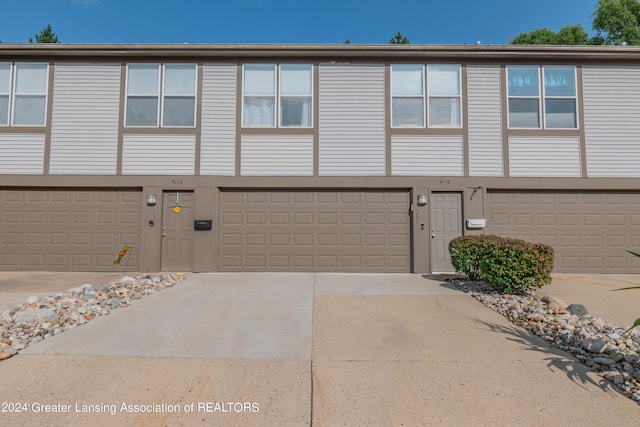 view of property featuring a garage, driveway, and stucco siding