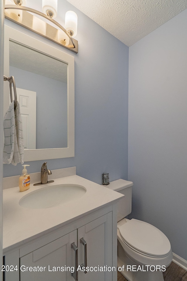 bathroom with a textured ceiling, toilet, and vanity