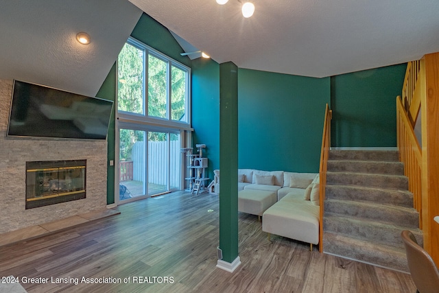 living room featuring a fireplace, a textured ceiling, lofted ceiling, and hardwood / wood-style floors