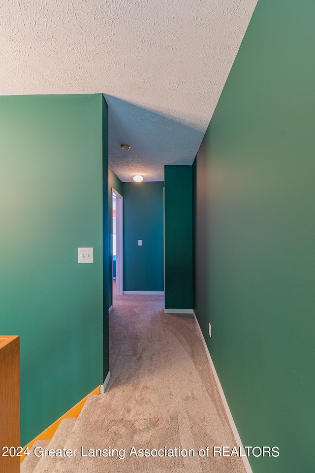 hall featuring a textured ceiling and carpet flooring