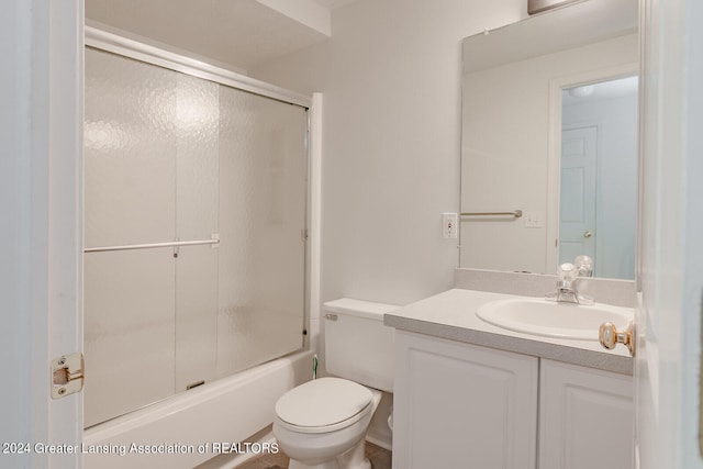 full bathroom with vanity, bath / shower combo with glass door, and toilet