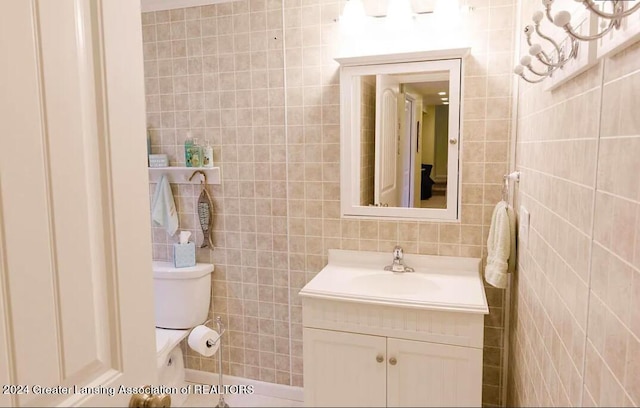 half bath featuring toilet, tile walls, and vanity