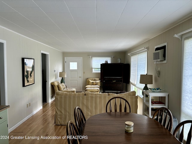 dining room with an AC wall unit, wood finished floors, and baseboards