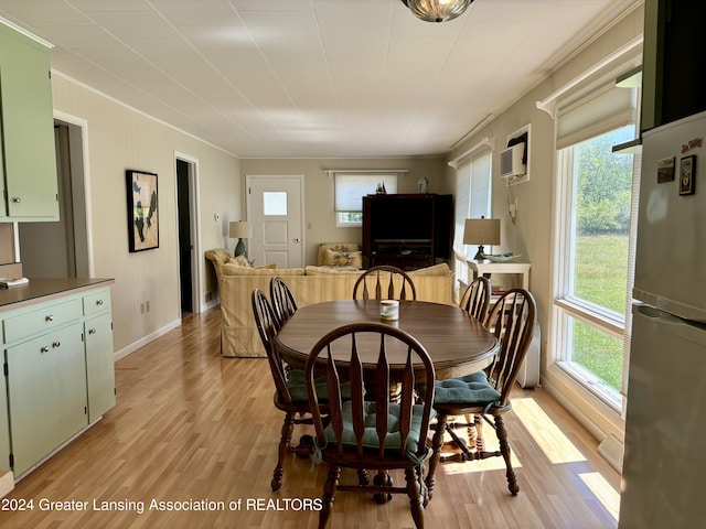 dining room featuring baseboards, ornamental molding, light wood-type flooring, and a wall mounted air conditioner