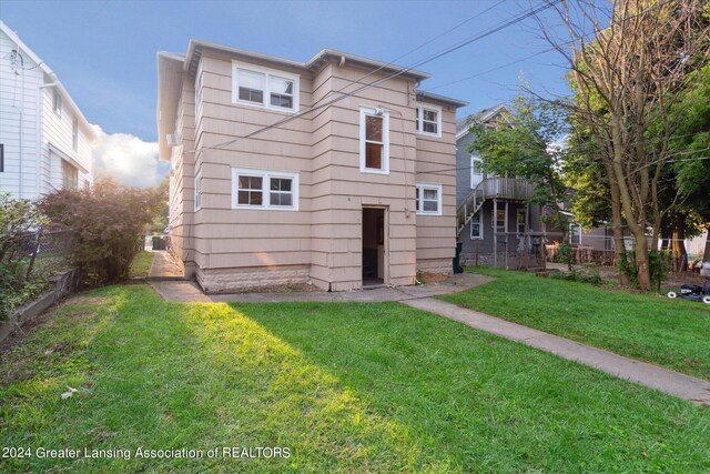 rear view of house with a lawn and fence