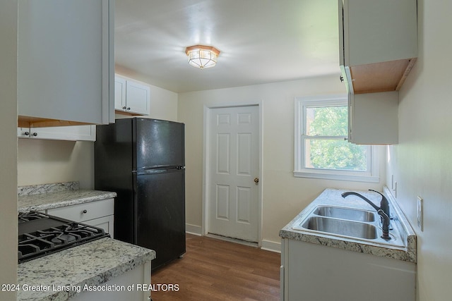 kitchen featuring light countertops, dark wood-type flooring, freestanding refrigerator, white cabinetry, and a sink