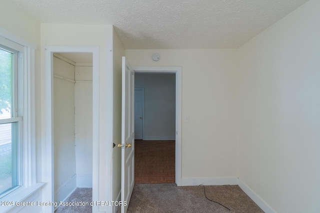 interior space featuring carpet floors, a textured ceiling, and baseboards