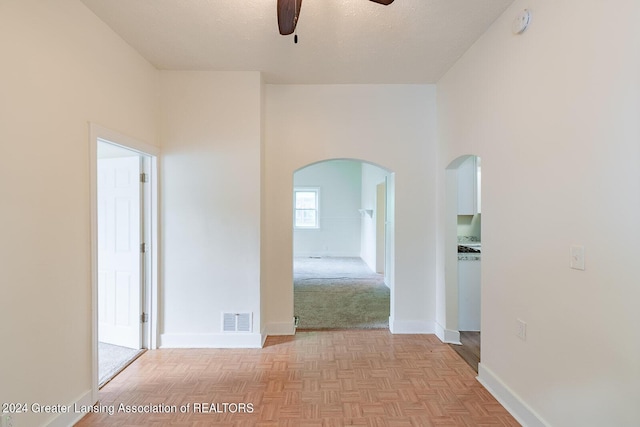 interior space featuring arched walkways, visible vents, a high ceiling, a textured ceiling, and baseboards