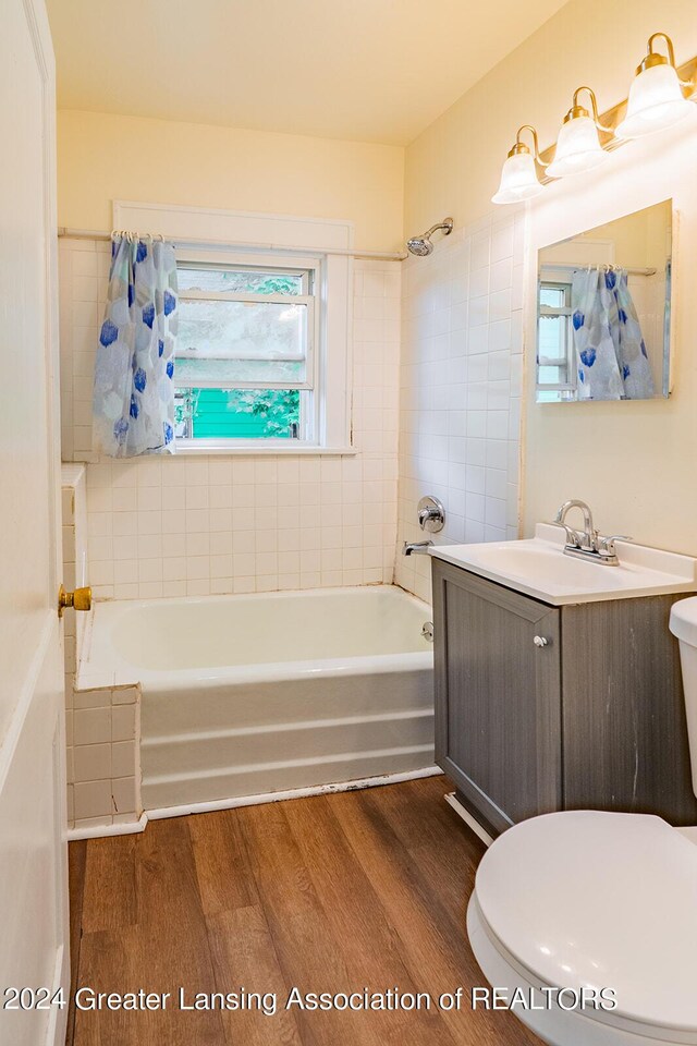 full bathroom featuring shower / tub combo with curtain, toilet, hardwood / wood-style flooring, and vanity