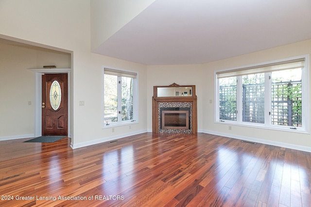 unfurnished living room with dark hardwood / wood-style floors and a tiled fireplace