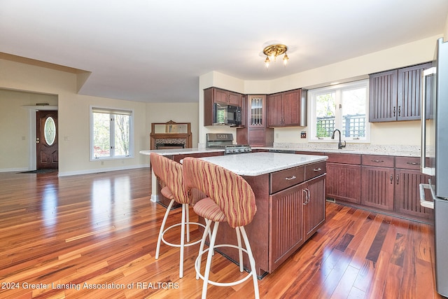 kitchen featuring dark wood-type flooring, a healthy amount of sunlight, black appliances, and a center island