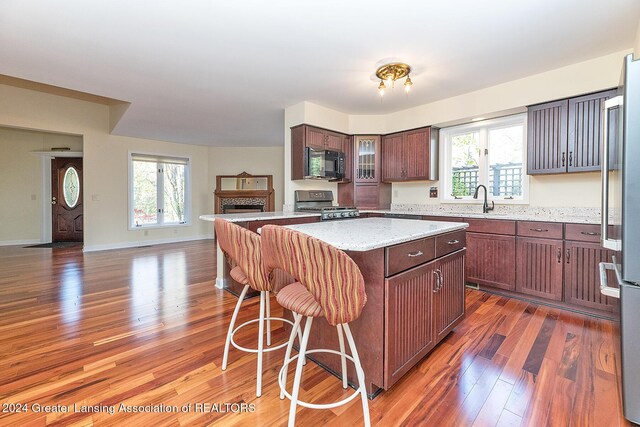 8425 Oakside St, Portage, MI 49002 - kitchen featuring black microwave, range, light wood-style floors, a sink, and a breakfast bar area
