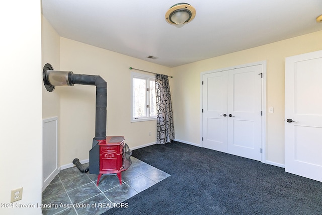 interior space featuring a wood stove and dark colored carpet