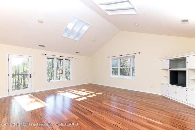 unfurnished living room with a wealth of natural light, wood-type flooring, high vaulted ceiling, and a skylight