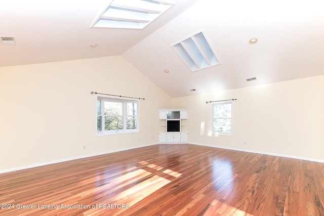 unfurnished living room with vaulted ceiling with skylight and wood-type flooring