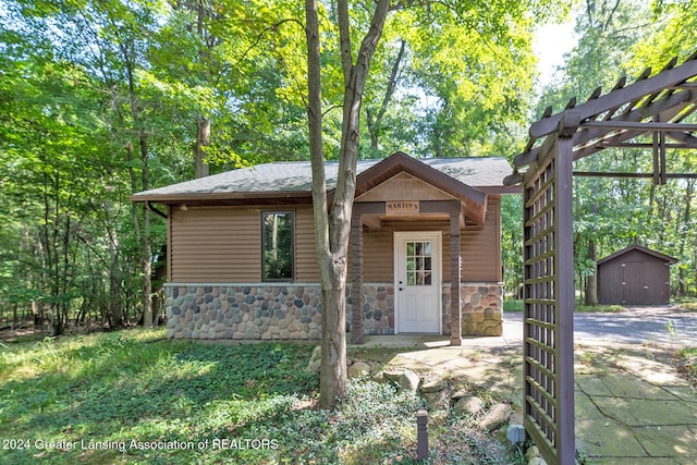 8425 Oakside St, Portage, MI 49002 - view of front of property featuring stone siding, roof with shingles, and an outdoor structure