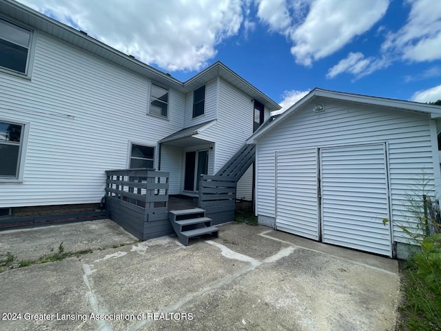 rear view of property featuring a wooden deck and a garage