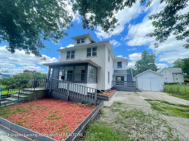 american foursquare style home featuring a detached garage, a storage unit, an outdoor structure, driveway, and a wooden deck