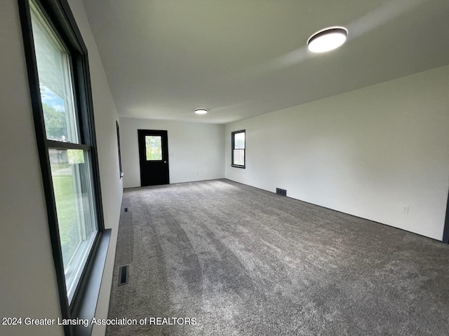 carpeted empty room featuring visible vents