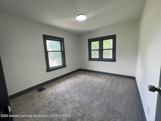 carpeted spare room with visible vents and baseboards