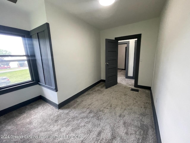 carpeted spare room with visible vents and baseboards