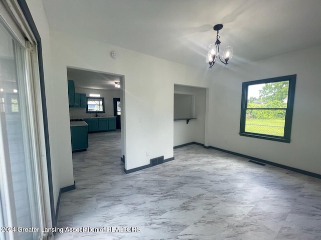 unfurnished room with an inviting chandelier and light tile patterned flooring