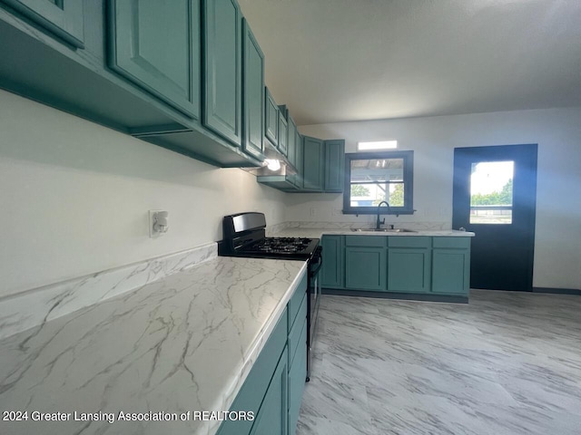 kitchen with black gas stove, sink, and light stone countertops