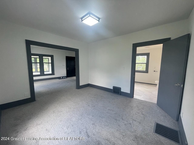 empty room with carpet, visible vents, and baseboards