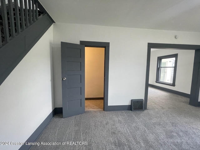 carpeted empty room featuring stairway, baseboards, and visible vents