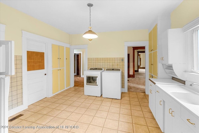 kitchen featuring tile walls, washing machine and dryer, sink, and hanging light fixtures