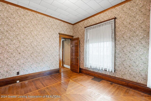 spare room with hardwood / wood-style floors and crown molding