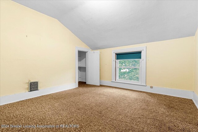 carpeted empty room with lofted ceiling