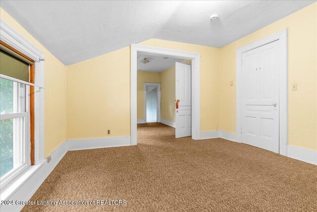 spare room featuring lofted ceiling and carpet flooring