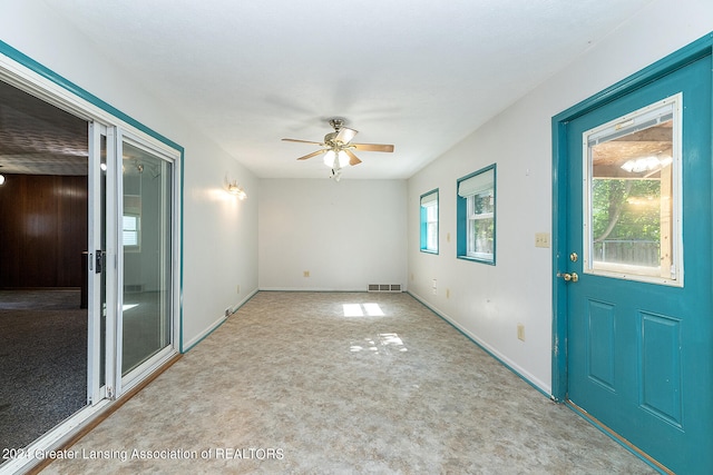 foyer with a wealth of natural light, ceiling fan, and light carpet