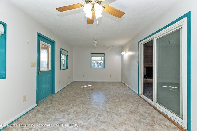 interior space with a textured ceiling, a wealth of natural light, and ceiling fan