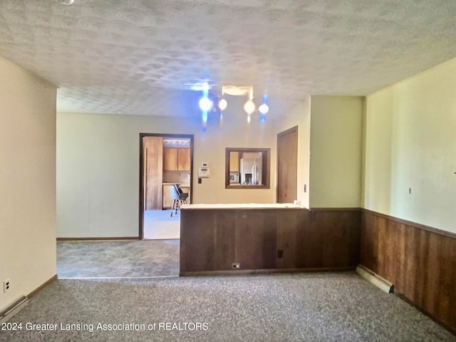 carpeted spare room featuring wood walls and a textured ceiling