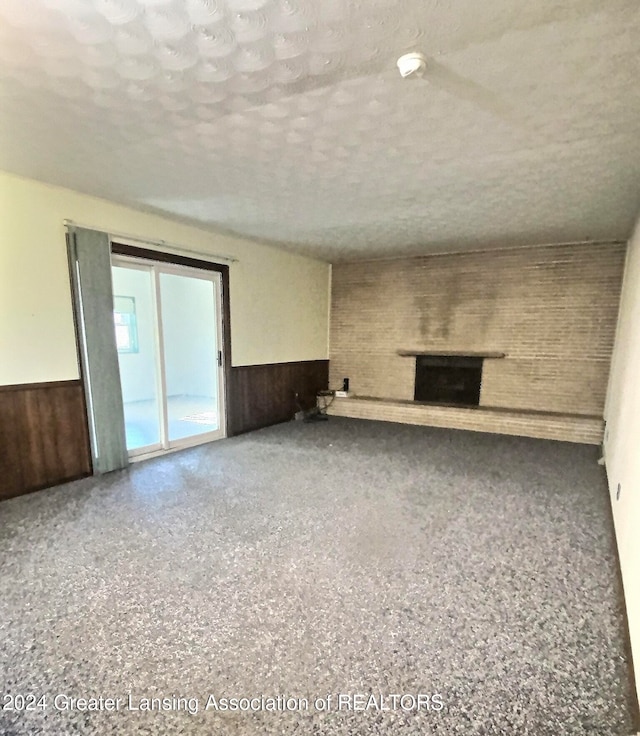 unfurnished living room featuring wood walls