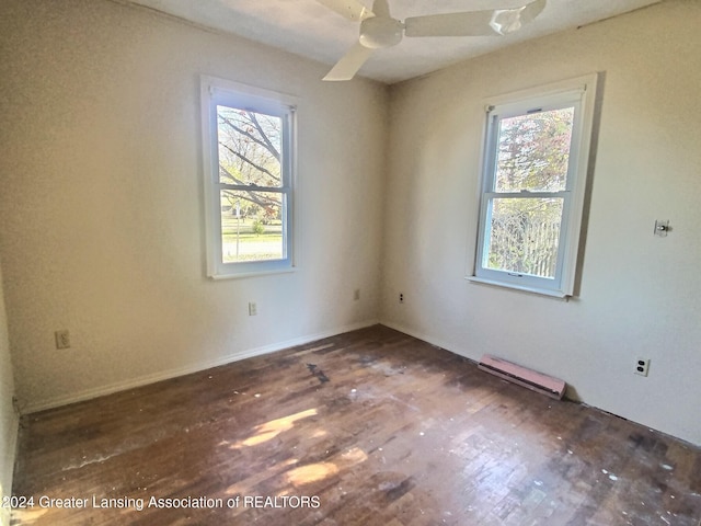 unfurnished room with dark wood-type flooring, ceiling fan, and a baseboard heating unit