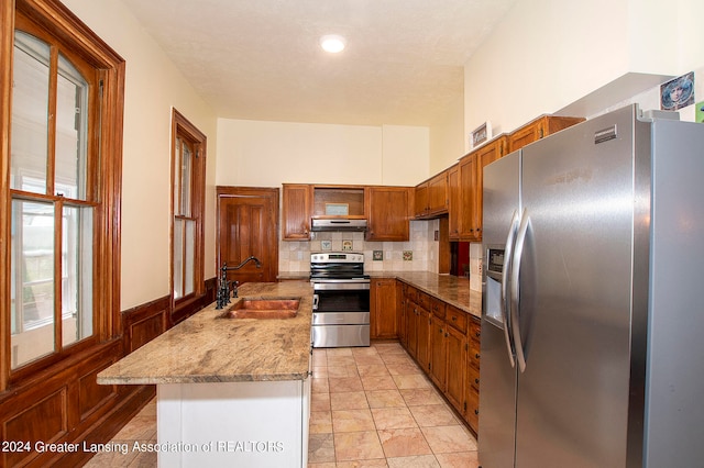 kitchen featuring light stone countertops, stainless steel appliances, sink, and decorative backsplash